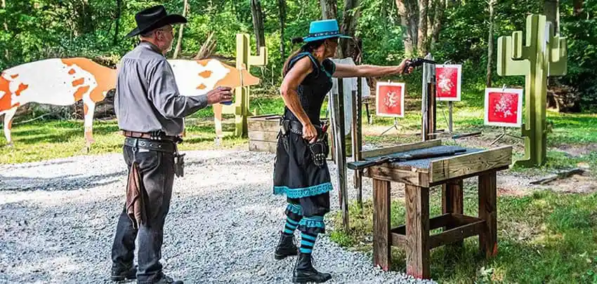participants-at-a-single-action-shooting-society-event-at-an-outdoor-range-featuring-western-style-props-and-targets