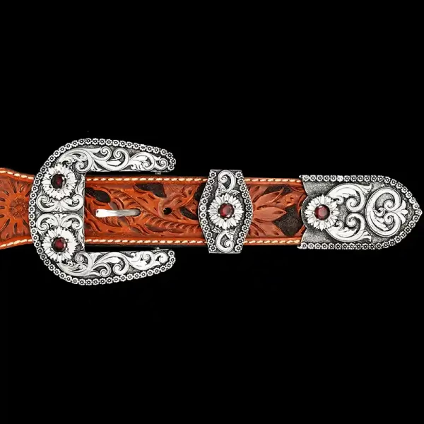 A custom western three piece belt buckle set featuring silver scrollwork and red zirconia stones