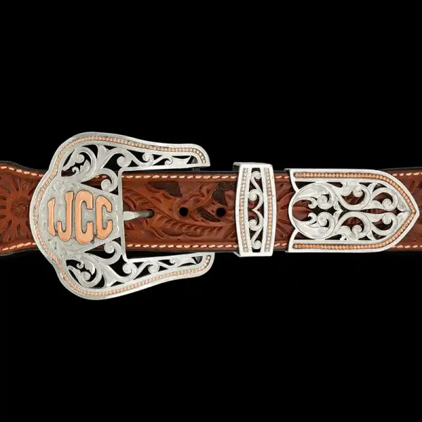 A custom western three piece belt buckle set featuring silver filigrane and a copper customizable ranch brand 