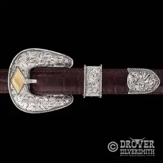 A sterling silver belt buckle set featuring a hand engraved base, rope frame and customizable lettering. 