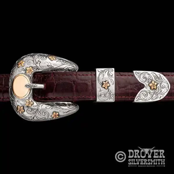 A sterling silver belt buckle set featuring golden bronze flowers and customizable lettering. 