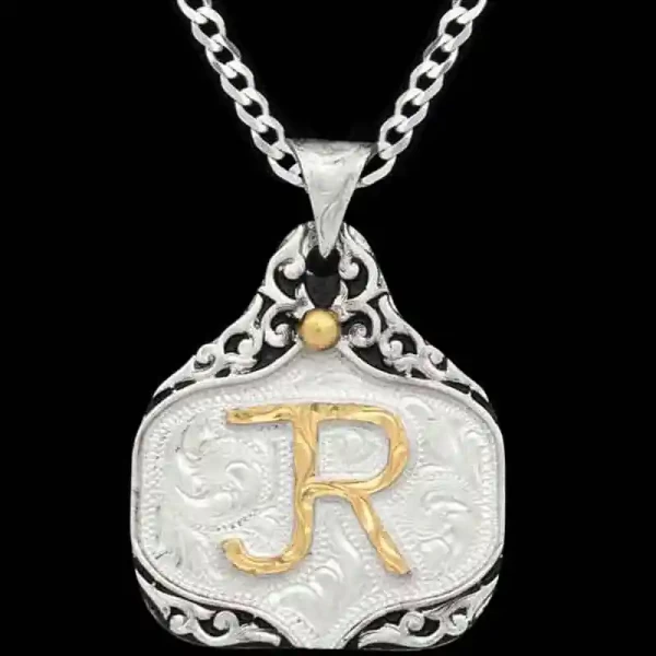 A hand engraved silver cow tag necklace featuring a golden custom ranch brand 