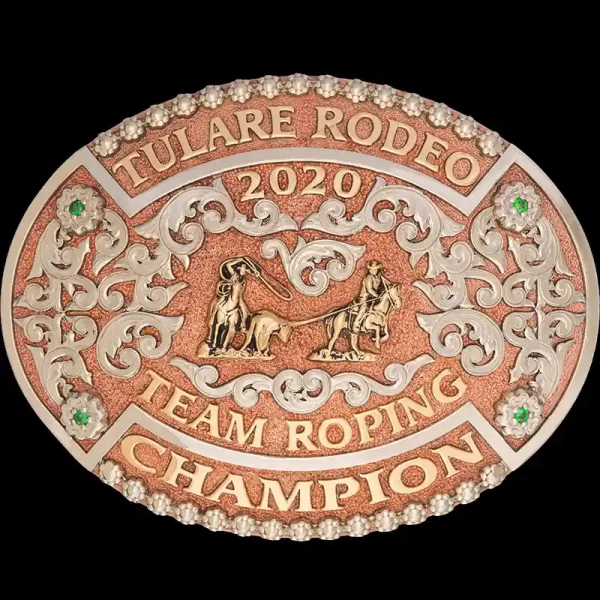 A custom oval rodeo belt buckle for Tulare Rodeo Team Roping Champion featuring a copper base and a team roper figure 