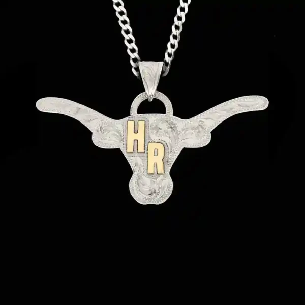 A custom pendant necklace built on a hand engraved silver base in the shape of a longhorn featuring bronze initials, with a sterling silver chain 