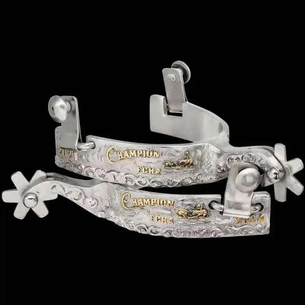 A custom pair of cowboy boot spurs with handmade details featuring personalized lettering and a team roping figure 