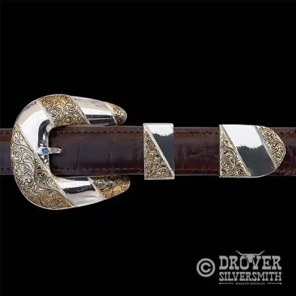 A sterling silver belt buckle set featuring a polished base with golden bronze hand engraved accents. 