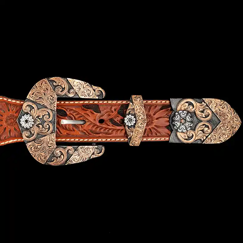 A custom western three piece belt buckle set featuring copper scrollwork