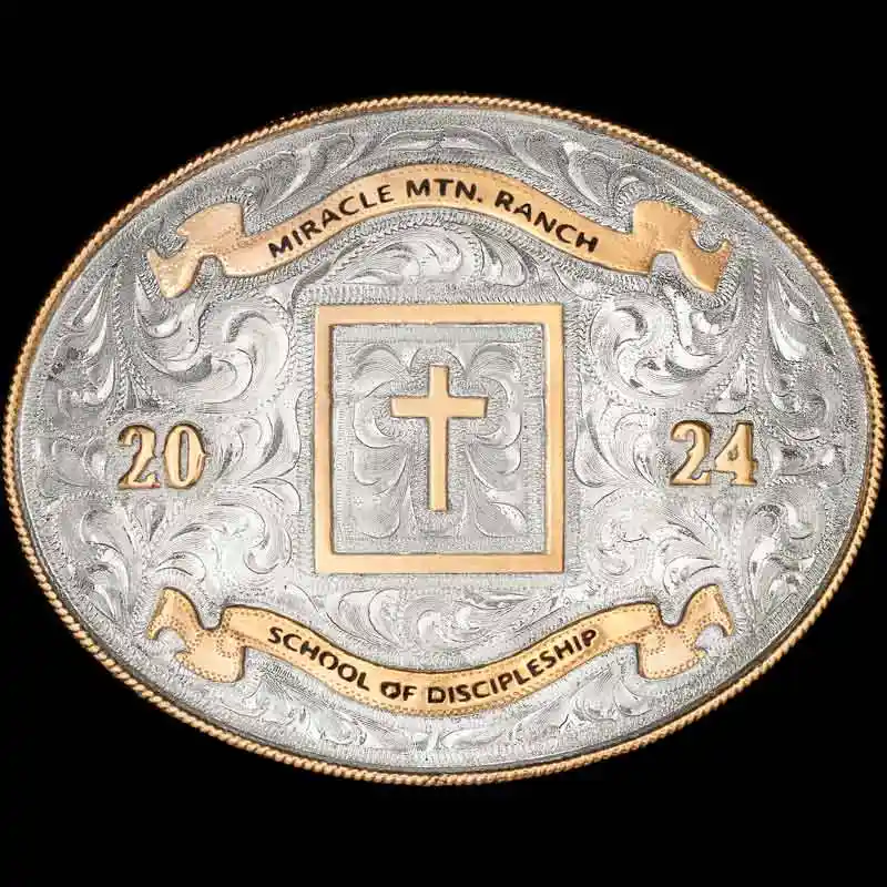 A custom oval silver western belt buckle featuring a cross figure
