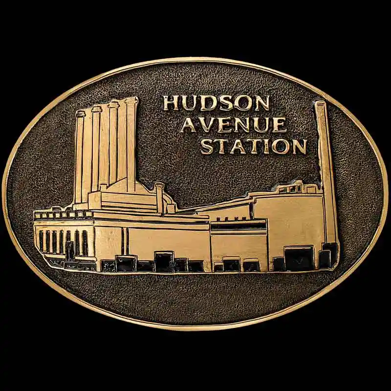 A custom oval personalized belt buckle built in a golden bronze base featuring Hudson Avenue Station custom logo