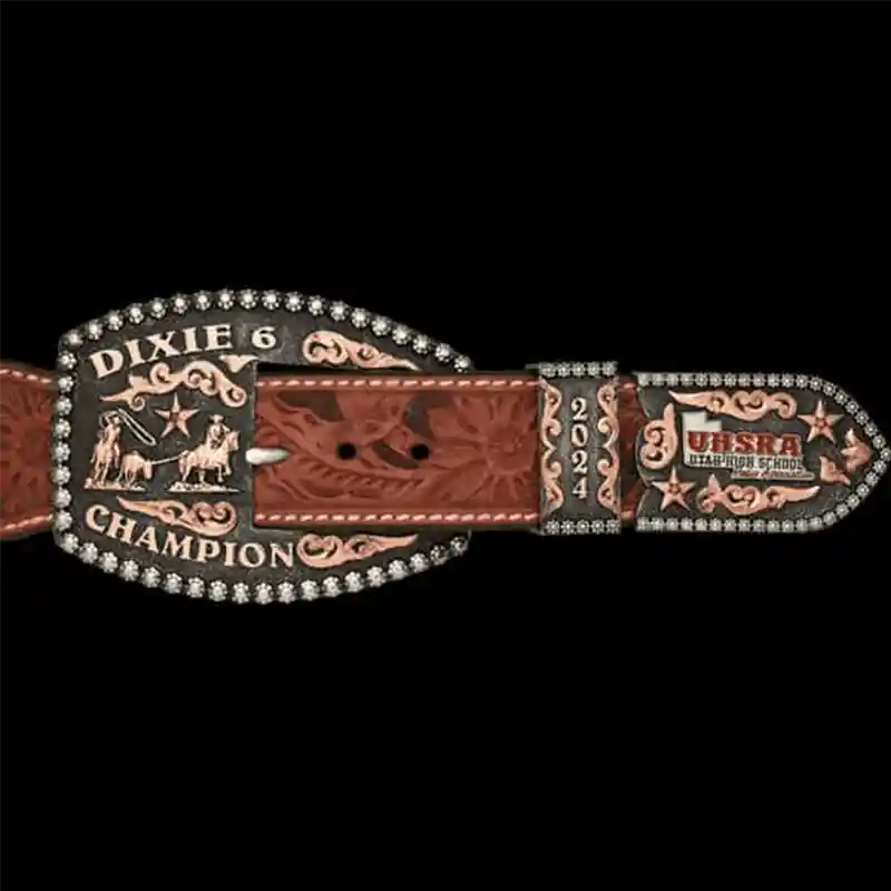 A custom western three piece belt buckle set featuring copper scrollwork with personalized lettering, custom logo and a team roping figure 