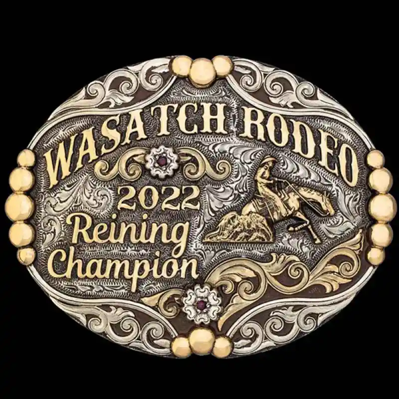 A custom oval rodeo belt buckle for Wasatch Rodeo Reining Champion featuring a reining cowboy figure